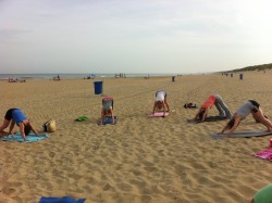Drie deelnemers in een balanshouding op het strand